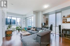 Toronto (Waterfront Communities) condo for rent - A living room with a grey couch and a wooden side table.