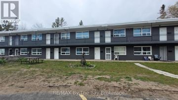 Wasaga Beach multi-family for rent - Apartment complex with a grassy area in front.