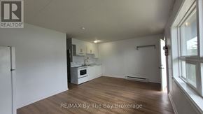 Wasaga Beach multi-family for rent - A spacious kitchen with white appliances and wooden floors.