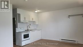 Wasaga Beach multi-family for rent - A white kitchen with a stove top oven and a sink.