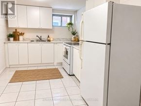 Richmond Hill (Crosby) apartment for rent - A white refrigerator stands in a kitchen with white cabinets and a brown rug on the floor.