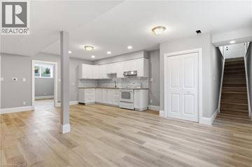 St. Agatha apartment for rent - A spacious kitchen with white cabinets and a staircase leading to another room.