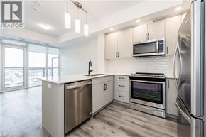 Kitchener condo for rent - A modern kitchen with stainless steel appliances and white cabinets.