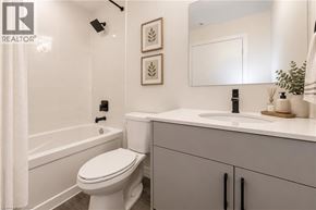 Kitchener condo for rent - A white toilet in a bathroom with a sink and a mirror.