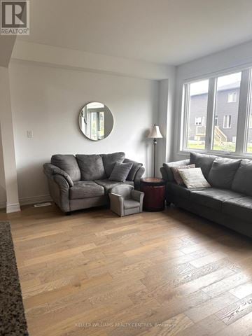 Wasaga Beach townhouse for rent - A living room with a grey couch and a round mirror on the wall.
