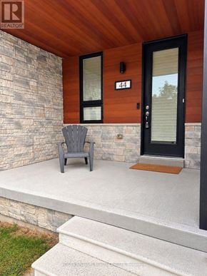 Wasaga Beach townhouse for rent - A grey chair is on a porch with a stone wall and a black door.
