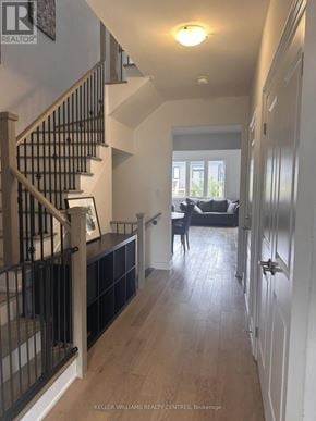 Wasaga Beach townhouse for rent - A hallway with a staircase and a couch in the background.