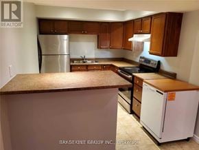 Brampton (Fletcher's Meadow) apartment for rent - A kitchen with a refrigerator, stove, and cabinets.