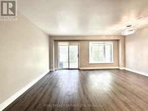 Mississauga (Applewood) townhouse for rent - A spacious room with wood flooring and a sliding glass door.