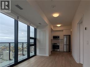 Kitchener condo for rent - A well-lit, empty apartment with a view of the cityscape outside.