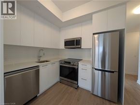 Kitchener condo for rent - A modern kitchen with white cabinets and stainless steel appliances.