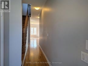 Southgate townhouse for rent - A hallway with a staircase on the left and a light at the end of the hallway.