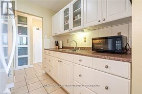 St. Catharines (Fairview) condo for rent - A kitchen with white cabinets and a black microwave.