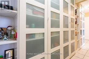 St. Catharines (Fairview) condo for rent - A white cabinet with glass doors is open, revealing a shelf with various items.