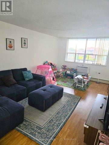 St. Catharines (Fairview) condo for rent - A living room with a blue couch and ottoman, a rug, and a television.