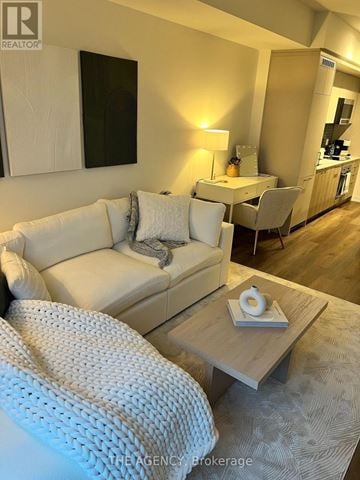Toronto (Wychwood) condo for rent - A white couch with a grey throw pillow sits in a living room.