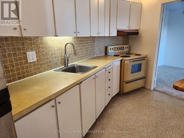 Ottawa condo for rent - A kitchen with white cabinets and a beige countertop.