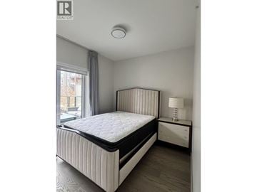 Vancouver townhouse for rent - A bedroom with a large bed and a nightstand with a lamp.