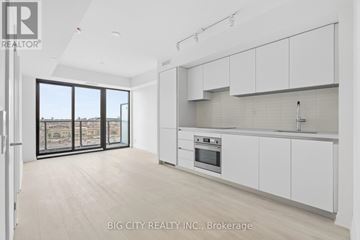 Toronto (Leaside) condo for rent - A modern kitchen with white cabinets and a large window.