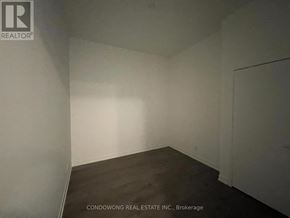 Toronto (South Parkdale) condo for rent - Empty room with white walls and dark floor.