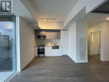Toronto (South Parkdale) condo for rent - A modern kitchen with white cabinets and a black countertop.