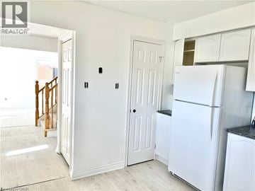 Grimsby apartment for rent - A white refrigerator stands in a kitchen next to a white door.