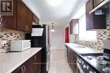 Brampton (Brampton North) apartment for rent - A kitchen with a white microwave and black refrigerator.