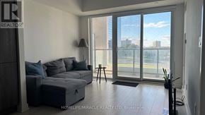 Toronto (Agincourt South-Malvern West) condo for rent - A living room with a grey sofa and a large window overlooking a cityscape.