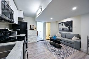 Toronto (South Riverdale) apartment for rent - A modern kitchen with a stainless steel stove and a black fridge.