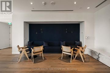 Toronto (Crescent Town) condo for rent - A living room with a dark blue couch and wooden chairs.