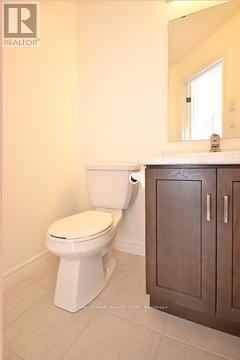 Guelph (Grange Road) townhouse for rent - A white toilet in a bathroom with a wooden cabinet.