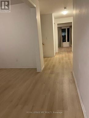 Niagara Falls (Brown) apartment for rent - A long hallway with wood floors and white walls.