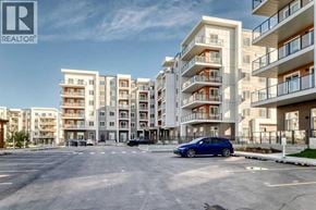 Calgary apartment for rent - A blue car is parked in a parking lot in front of apartment buildings.