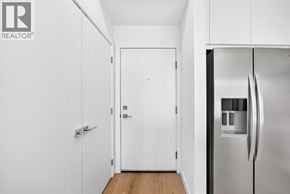 Calgary apartment for rent - A white door is in a hallway with a refrigerator on the right.