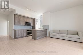 Toronto (Annex) condo for rent - A modern kitchen with a microwave above the oven and a couch in the living room.