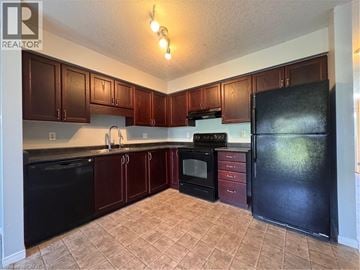 Kitchener townhouse for rent - A kitchen with brown cabinets and black appliances.