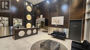 Toronto (Bendale) condo for rent - A modern office lobby with a reception desk and a black couch.