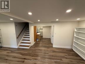 Newmarket (Gorham-College Manor) apartment for rent - A room with wooden flooring and white walls, with a staircase on the left and a door on the right.