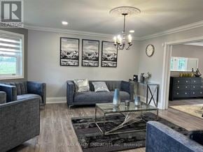 New Tecumseth apartment for rent - A living room with a grey couch, a glass coffee table, and a chandelier.