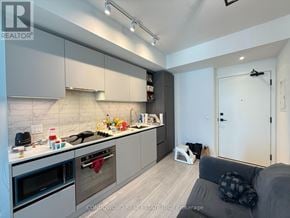 Toronto (Waterfront Communities) condo for rent - A modern kitchen with a grey couch and a white toaster.