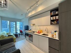 Toronto (Waterfront Communities) condo for rent - A modern kitchen with white cabinets and a large window.