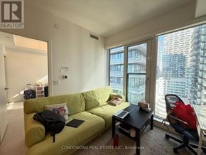 Toronto (Waterfront Communities) condo for rent - A bright living room with a green couch and a table with a laptop on it.
