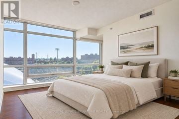 Toronto (South Parkdale) condo for rent - A bedroom with a large bed and a view of the city.