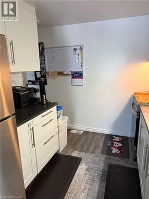 Guelph townhouse for rent - A kitchen with white cabinets and a black fridge.