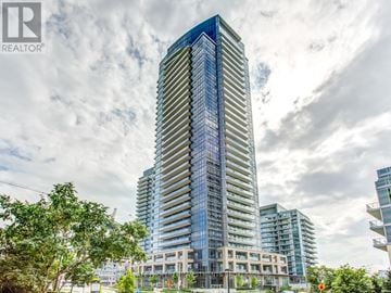 Toronto (Henry Farm) condo for rent - A tall, modern glass skyscraper stands in the foreground of a cloudy day.
