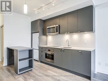 Toronto (Henry Farm) condo for rent - A modern kitchen with a white refrigerator and grey cabinets.