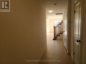 Brant (Paris) townhouse for rent - A hallway with a wooden staircase and white walls.