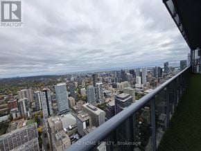 Toronto (Bay Street Corridor) condo for rent - A cityscape viewed from a balcony with a sign that reads "Right at Home Realty, Brokerage".