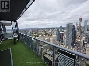 Toronto (Bay Street Corridor) condo for rent - A balcony with a table and chairs overlooking a city skyline.