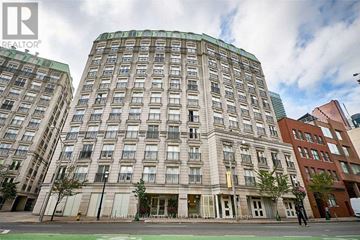 Toronto (Church-Yonge Corridor) condo for rent - A large building with a curved top is in the foreground with a street in front of it.